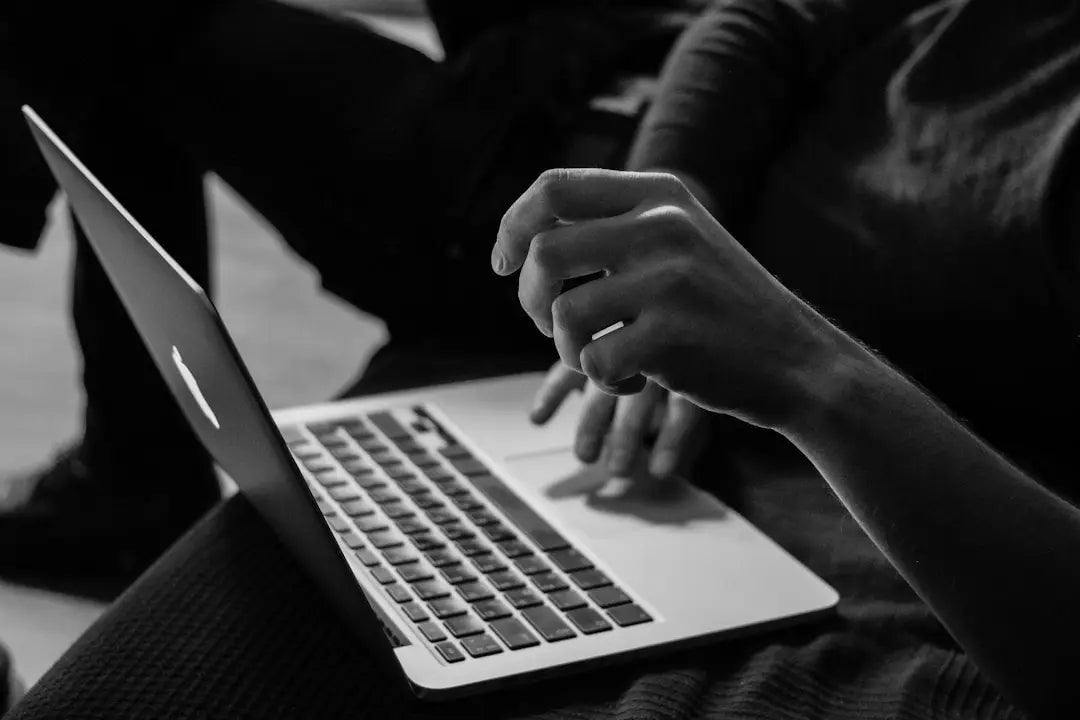 Hands typing on a laptop for researching online stores for wall decor and picture framing