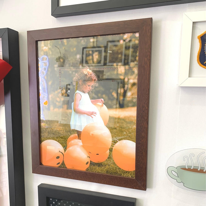 Framed photograph of a child with pumpkins in 9x37 picture frame on grass