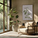 Armchair with beige upholstery and wooden frame beside Botanical Cycling Framed Art